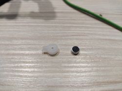 A rubber gasket and a sensor lying on a wooden surface.