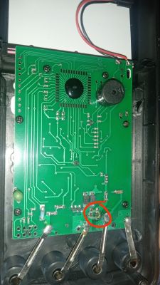 Image of the interior of a DT-9205A multimeter with a red circle marking a damaged component on the circuit board.