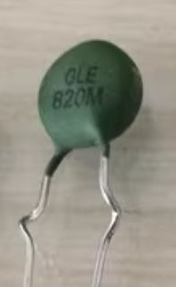 Zielony termistor oznaczony jako GLE 820M z dwoma metalowymi nóżkami