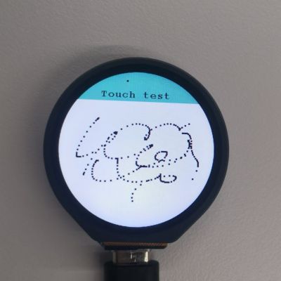 Okrągły ekran modułu ESP32-S3-Touch-LCD-1.28 z wyświetlonym testem dotyku i śladem w formie czarnych kropek.