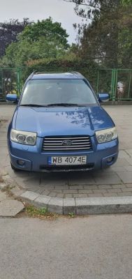 Blue Subaru car parked on a sidewalk.