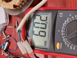 Cyfrowy multimetr z odczytem 602 na wyświetlaczu, otoczony przewodami i drobnymi elementami elektronicznymi.