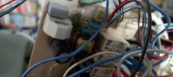 Zbliżenie na panel elektroniczny z różnymi kablami i elementami elektronicznymi.