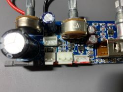 Zbliżenie na płytkę drukowaną z różnymi elementami elektronicznymi, w tym kondensatorami, potencjometrami i mikrokontrolerem.