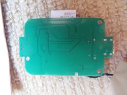 Green, rectangular printed circuit board with visible traces on a beige background.