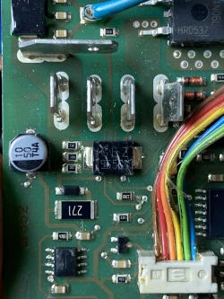 Nahaufnahme einer beschädigten Elektronikplatine mit sichtbaren Bauteilen.