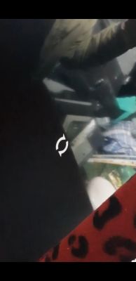 Screenshot or photo of a device screen with a loading icon and the reflection of a person and various items in the background.