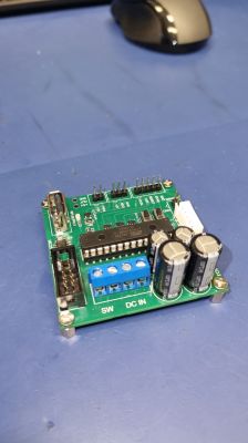 PCB with power supply and LED control components Soldered PCB with pins, capacitors, and connectors on a blue work surface