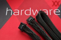Zbliżenie na dwa czarne przewody z oznaczeniem „600W” na tle czerwonego materiału z napisem „hardware”.