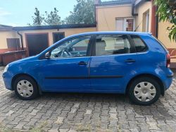 Blue Volkswagen car parked in a driveway in front of a residential building.