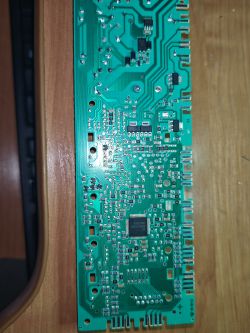 Zdjęcie tylnej strony płytki drukowanej z elementami elektronicznymi.