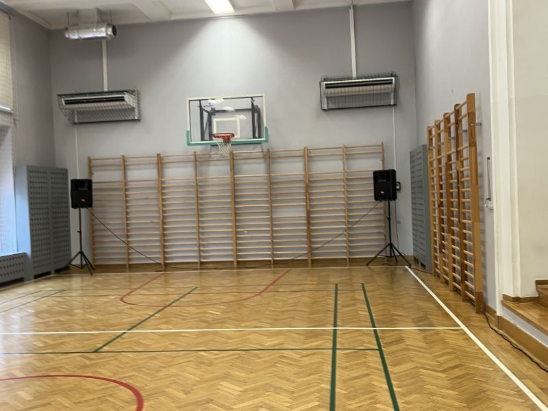 Ustawienie głośników w sali gimnastycznej do nagłośnienia teatralnego Dwa głośniki pasywne ustawione na statywach w sali gimnastycznej przy drabinkach