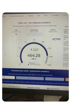 Wynik testu prędkości internetu z pobieraniem 464,28 Mb/s i pingiem 14 ms na ekranie monitora