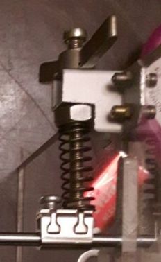 Metalowy mechanizm z sprężyną i kilkoma śrubami.