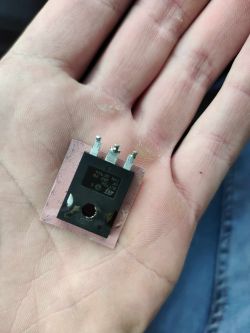 Tranzystor STMicroelectronics na dłoni z widocznymi trzema wyprowadzeniami.