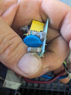 Ujęcie z bliska obwodu zasilacza LED w dłoni, pokazujące elementy elektroniczne i przewody.