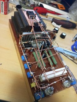 Samodzielnie zbudowany wzmacniacz audio na drewnianej płytce ze skomplikowanym podłączeniem przewodów i komponentów elektronicznych.