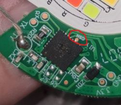 Close-up of a circular circuit board with electronic components and an LED.