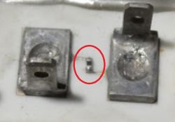 Dwa metalowe styki i mały termistor SMD umieszczony pomiędzy nimi, zaznaczony czerwonym okręgiem.