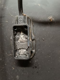 Zbliżenie na uszkodzoną puszkę elektryczną panelu solarnego z przepalonym stykiem.