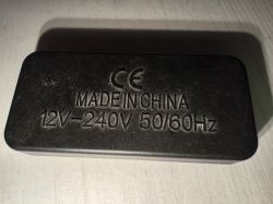 Czarna obudowa zasilacza z nadrukiem MADE IN CHINA 12V-240V 50/60Hz.