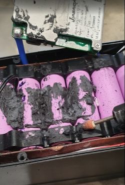 Pakiet ogniw cylindrycznych pokryty czarną masą termoprzewodzącą, obok narzędzie do szlifowania.