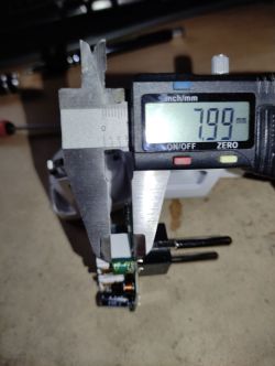 Measuring an Electronic Component with a Digital Caliper A digital caliper measures an electronic component on a circuit board, displaying 7.99 mm.