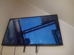 Ekran telewizora wyświetlający grę wideo z widokiem na mostek pomiędzy dwoma budynkami na tle nieba.