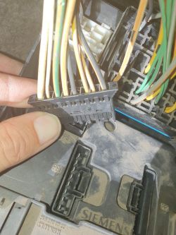 Zbliżenie na kostkę z przewodami w samochodzie, obok modułu Siemens.