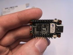 Moduł ESP32 trzymany w dłoni z widocznym portem USB-C i złączami pinowymi