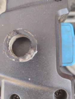 Uszkodzone mocowanie noża kosiarki elektrycznej z widoczną tuleją montażową.