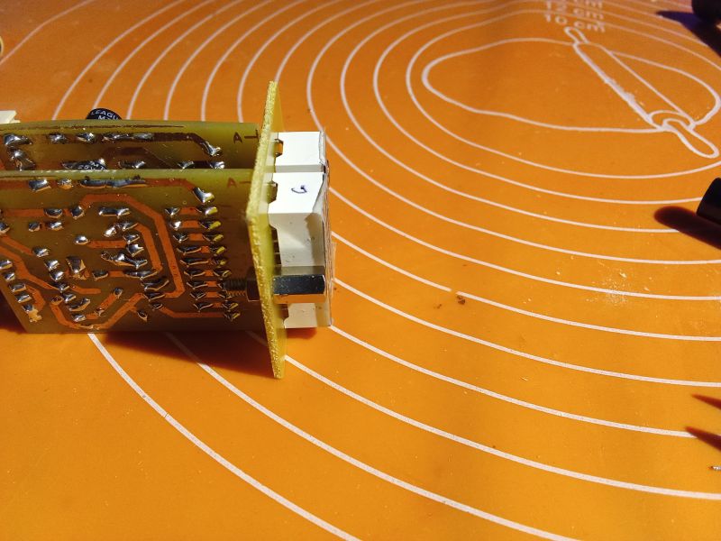 A printed circuit board placed on an orange mat with white circles.