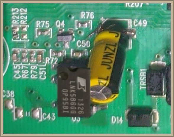Zbliżenie na płytkę drukowaną z różnymi komponentami elektronicznymi, w tym kondensatorem oznaczonym jako C49 i układem scalonym.