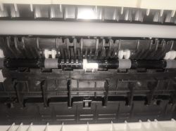 Widok zbliżony na mechanizm rolek i plastikowych prowadnic w drukarce.