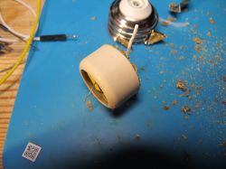 Lamp socket component and its parts on a blue mat, surrounded by small debris.