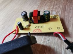 Płytka PCB z elementami zasilacza, kondensatorami i diodą LED na drewnianej powierzchni