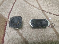 Two small speakers on a carpet, one square and one rectangular