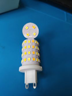 Disassembled Tuya G9 LED Bulb Disassembled Tuya G9 smart LED bulb on a blue background.
