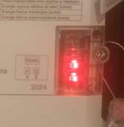 Zbliżenie na trójfazowy licznik zdalnego odczytu z widoczną czerwoną diodą PWR oraz migającą diodą STR.