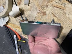 Ogniwo Li-ion w obudowie aluminiowej trzymane w ręce na tle stołu warsztatowego
