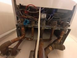 Widok na dolną część pieca gazowego Junkers z rurami i zaworami.