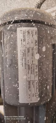 Close-up of a dirty cylindrical electric motor with a specification label.