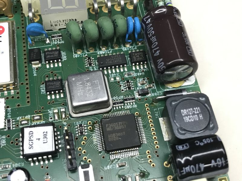 Close-up of PCB with electronic components, including quartz crystal and capacitors.