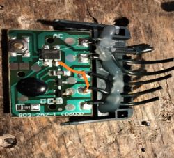 Zbliżenie na płytkę drukowaną z elementami elektronicznymi, z zaznaczonym mostkiem z drutu.