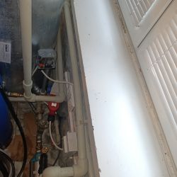 Instalacja hydrauliczna z pompą, rurami i zaworami w pomieszczeniu.