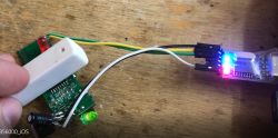 Close-up of an electronic circuit with a white sensor, colored wires, and glowing LEDs.