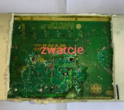 Zbliżenie płytki PCB z podpisem „zwarcie” i strzałkami wskazującymi uszkodzony obszar