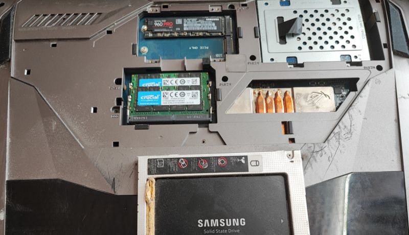 Exposed Laptop Interior with Components Open laptop underside with visible internal components, including a Samsung SSD and Crucial RAM.