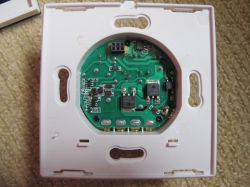 Open case of a touch light switch showing the circuit board with electronic components inside.
