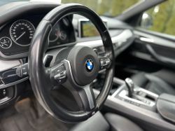 Interior of a BMW car, view of the steering wheel and dashboard.